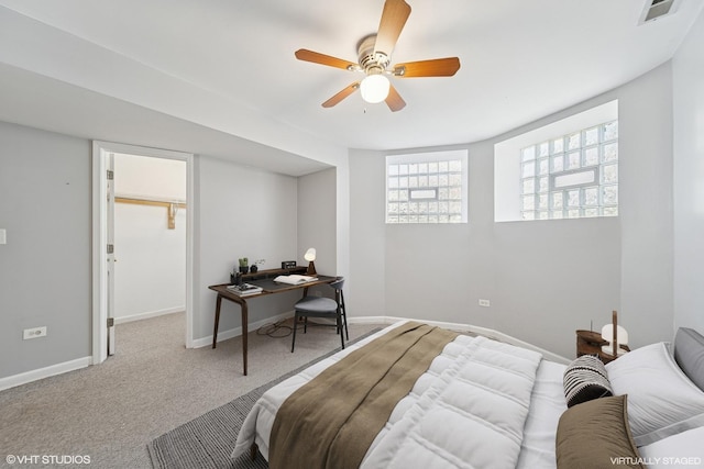 carpeted bedroom with a ceiling fan, a walk in closet, baseboards, and visible vents