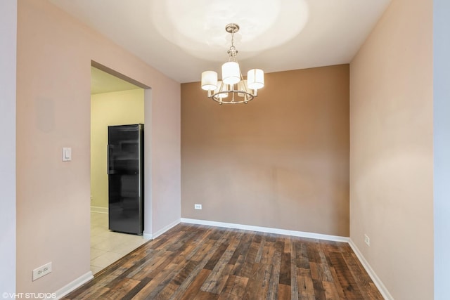 unfurnished room featuring hardwood / wood-style flooring, baseboards, and a chandelier