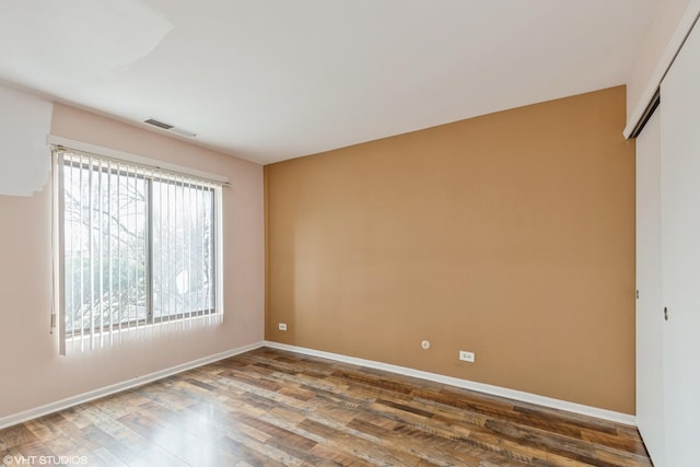 unfurnished room featuring visible vents, baseboards, and wood finished floors