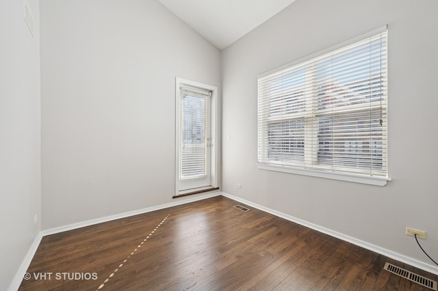 spare room with baseboards, visible vents, dark wood-style floors, and lofted ceiling