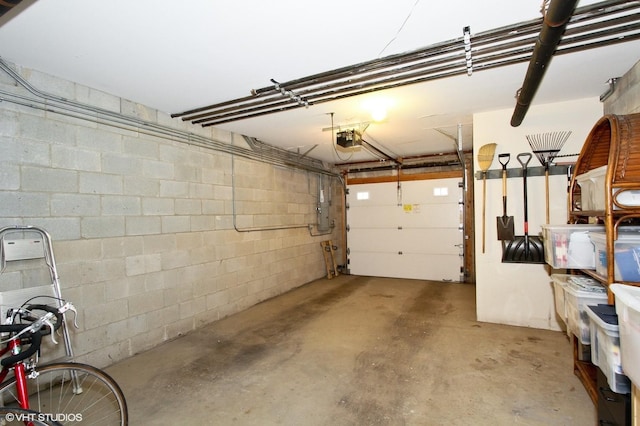 garage with concrete block wall, a garage door opener, and electric panel