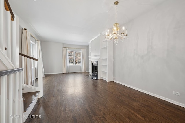 unfurnished living room featuring baseboards, dark wood finished floors, an inviting chandelier, and a fireplace
