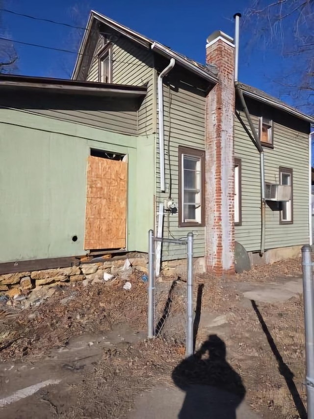 view of property exterior with cooling unit and a chimney