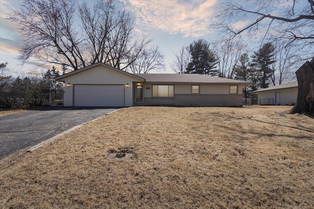 ranch-style home with aphalt driveway, an attached garage, and brick siding