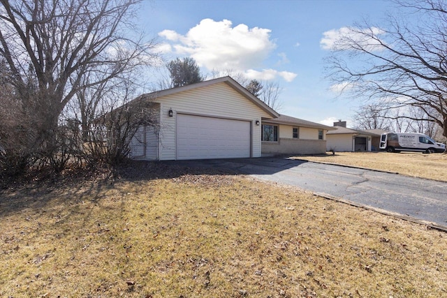 single story home with a chimney, driveway, and an attached garage