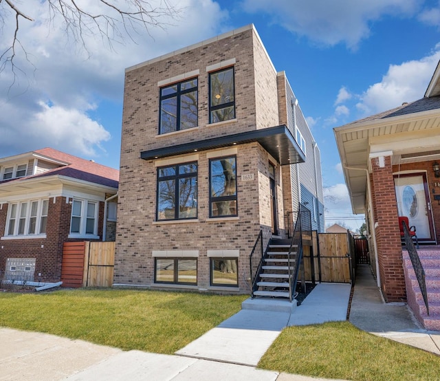 view of front of property featuring fence, brick siding, a front yard, and a gate