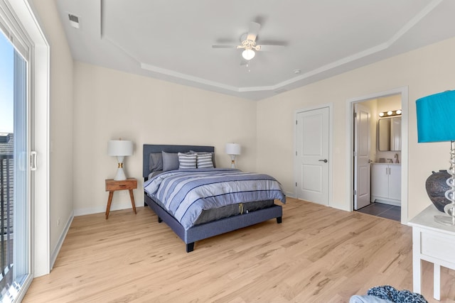 bedroom with visible vents, connected bathroom, baseboards, light wood-style flooring, and a raised ceiling