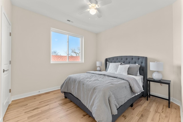 bedroom with light wood-type flooring, visible vents, baseboards, and a ceiling fan