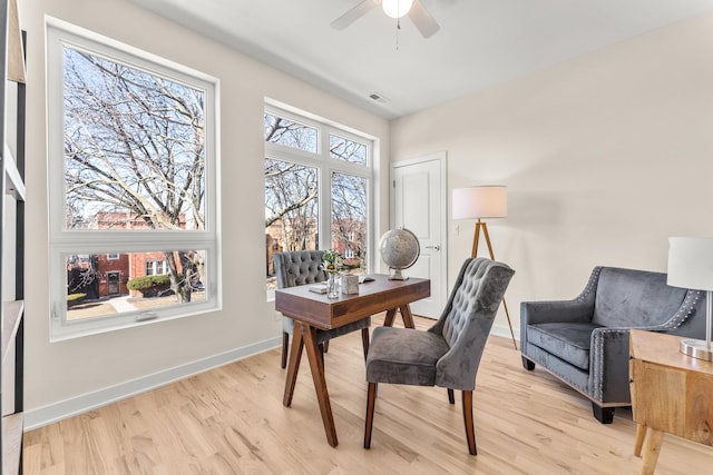 home office with light wood-type flooring, baseboards, visible vents, and a ceiling fan