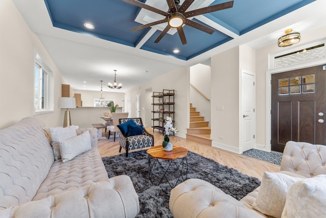 living room featuring stairway, coffered ceiling, baseboards, and wood finished floors