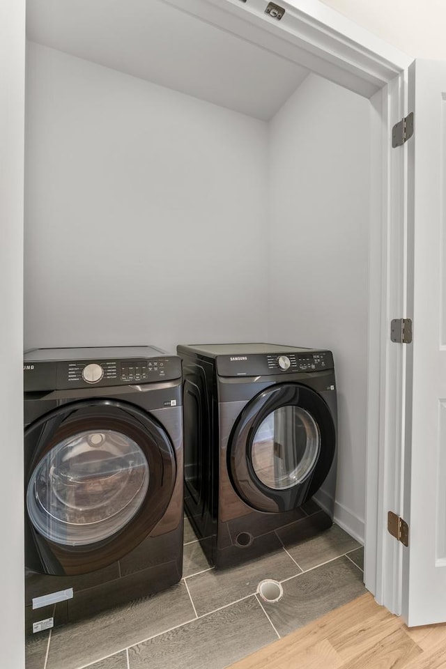 laundry room featuring separate washer and dryer, wood finished floors, and laundry area