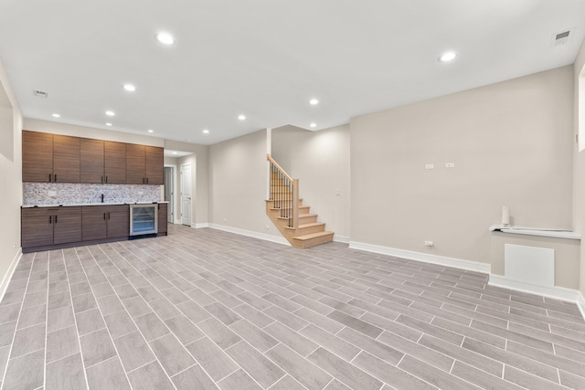 unfurnished living room with visible vents, recessed lighting, wine cooler, baseboards, and stairs