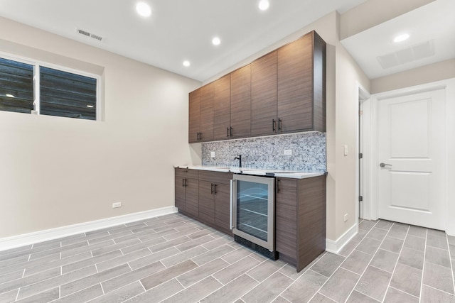 bar with visible vents, wine cooler, backsplash, and indoor wet bar