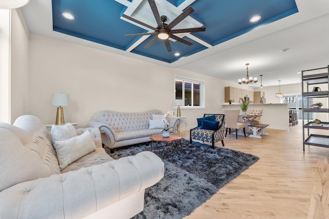 living area with ceiling fan with notable chandelier, coffered ceiling, wood finished floors, recessed lighting, and baseboards