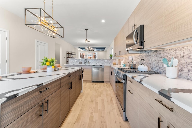 kitchen with stainless steel appliances, tasteful backsplash, a notable chandelier, and light wood-style flooring