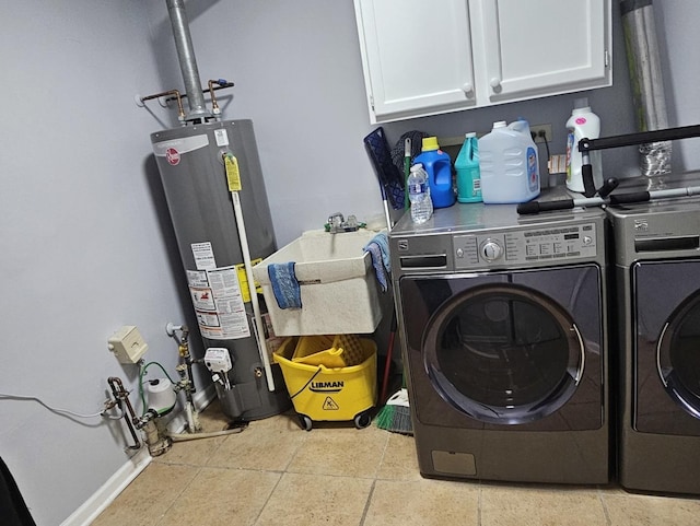 washroom with water heater, washer and dryer, cabinet space, and baseboards