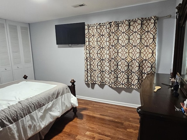 bedroom with visible vents, baseboards, and wood finished floors