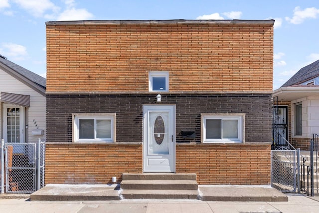 view of front of house with brick siding, entry steps, a gate, and fence