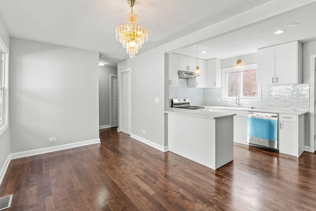 kitchen with dark wood-style floors, stainless steel appliances, under cabinet range hood, pendant lighting, and backsplash