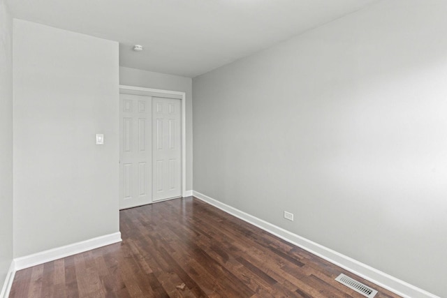 unfurnished bedroom with visible vents, baseboards, a closet, and dark wood finished floors