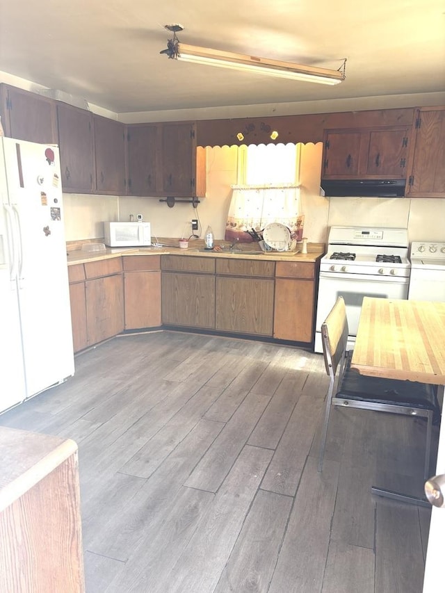 kitchen featuring white appliances, washer / dryer, light wood-style flooring, light countertops, and under cabinet range hood