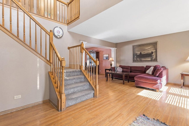 stairway with decorative columns, baseboards, and wood finished floors