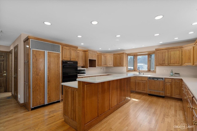 kitchen featuring paneled appliances, a center island, light countertops, recessed lighting, and light wood-style floors