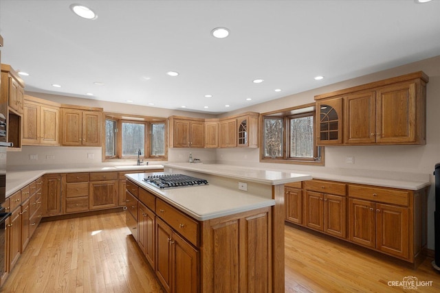 kitchen featuring a sink, light wood-style flooring, a kitchen island, and stainless steel gas stovetop