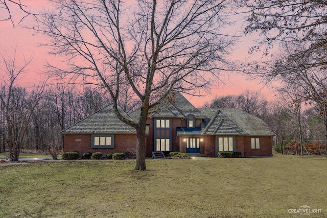 view of front of home featuring a yard and brick siding