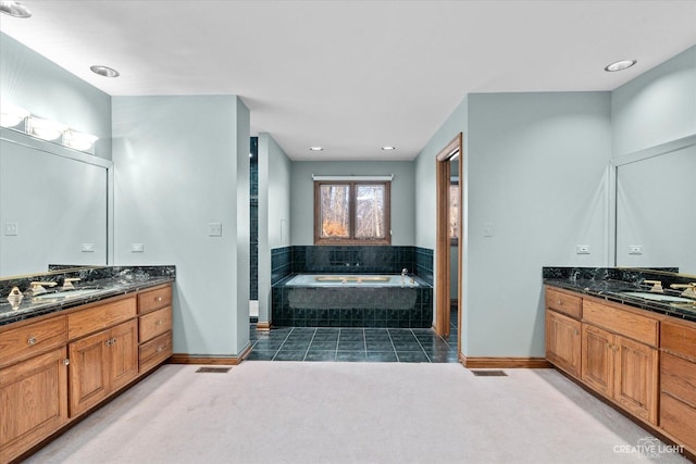 bathroom with a sink, visible vents, a garden tub, and two vanities