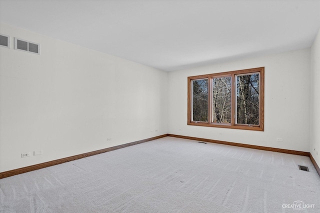 unfurnished room with visible vents, light colored carpet, and baseboards