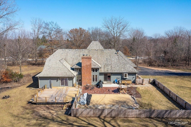 rear view of property with a wooden deck, a fenced backyard, a chimney, a patio area, and a lawn