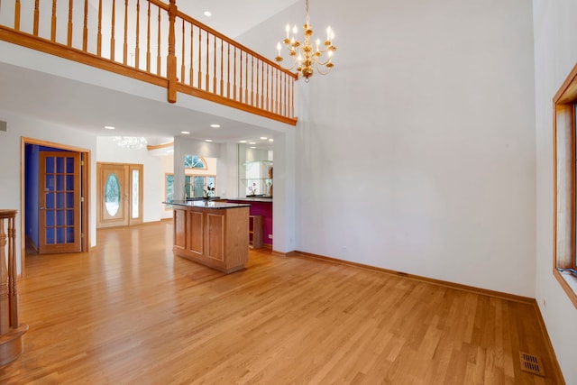 unfurnished living room featuring visible vents, baseboards, a notable chandelier, and light wood-style flooring