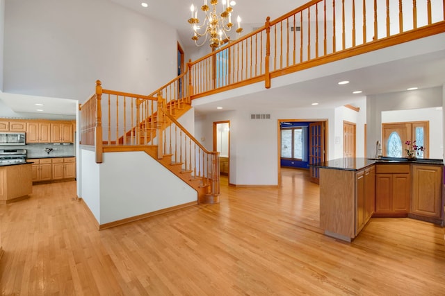 kitchen with visible vents, dark countertops, stainless steel appliances, a high ceiling, and light wood finished floors