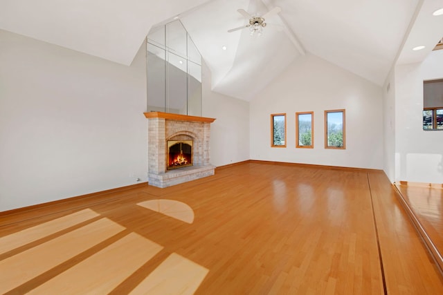 unfurnished living room featuring a healthy amount of sunlight, a brick fireplace, high vaulted ceiling, and wood finished floors