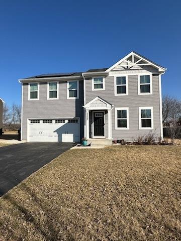 view of front facade with aphalt driveway, solar panels, and an attached garage