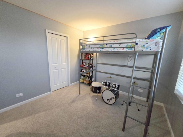 carpeted bedroom with a closet and baseboards