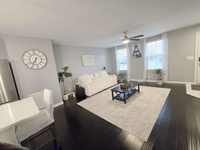 living room featuring baseboards, dark wood-type flooring, and a ceiling fan