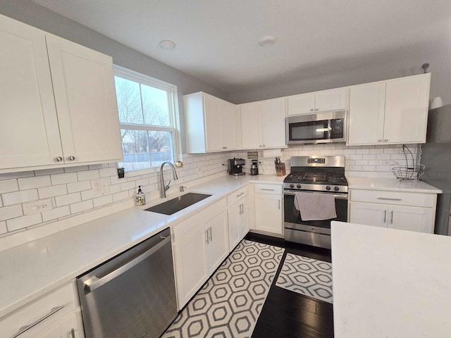 kitchen featuring a sink, white cabinetry, appliances with stainless steel finishes, light countertops, and decorative backsplash