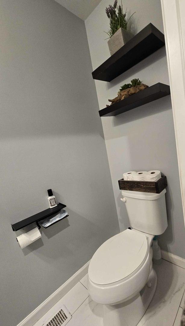 bathroom featuring toilet, baseboards, and marble finish floor