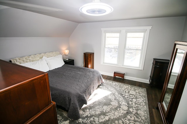 bedroom with baseboards, lofted ceiling, and wood finished floors