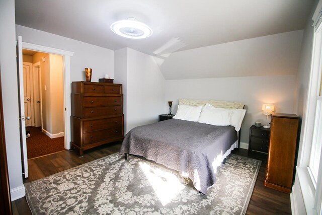 bedroom featuring baseboards, dark wood finished floors, and vaulted ceiling