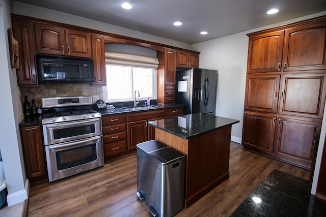 kitchen with dark wood-type flooring, black appliances, a sink, a kitchen island, and decorative backsplash