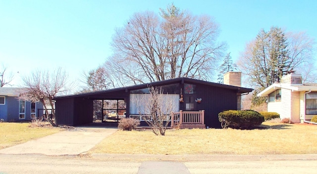 mid-century inspired home with driveway, a carport, and a chimney