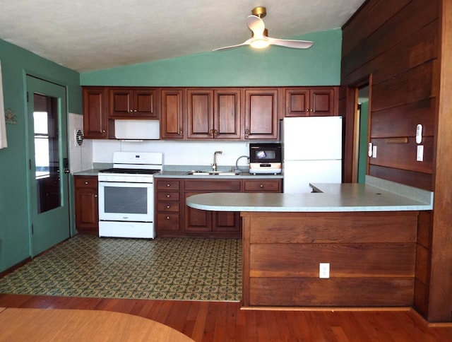 kitchen featuring vaulted ceiling, white appliances, light countertops, and a sink