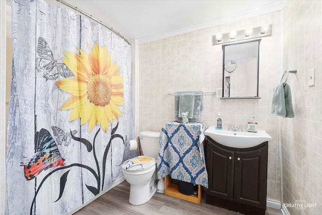 full bath featuring toilet, ornamental molding, wood finished floors, tile walls, and vanity