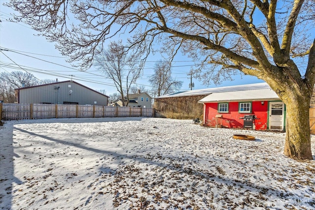 yard covered in snow with an outbuilding and fence