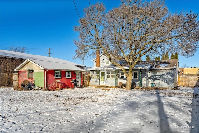 view of front of house featuring a garage, fence, and a sunroom