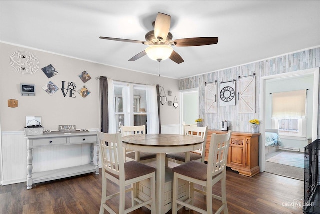 dining area with a ceiling fan, dark wood-style floors, wainscoting, and crown molding