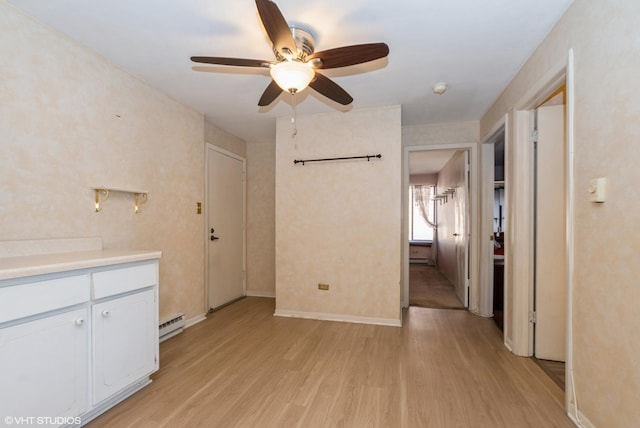 interior space with ceiling fan, baseboards, light wood finished floors, and a baseboard radiator